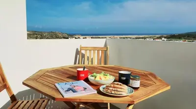 a wooden table with a bowl of food on a balcony at Casa Bombordo in Carrapateira