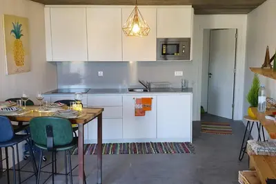 a kitchen with a table and chairs and a kitchen with white cabinets at Casa Bombordo in Carrapateira