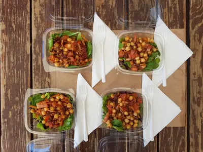 four plastic containers of food on a wooden table at Russo Surf Resort - Vale Figueiras in Aljezur