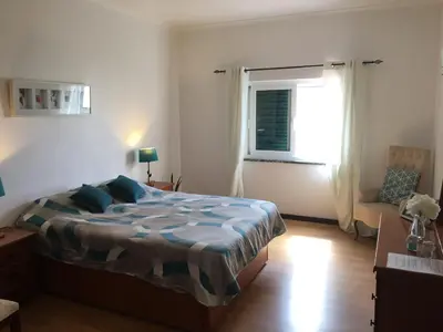 a bedroom with a bed and a window and a chair at Casa Maré in Sagres
