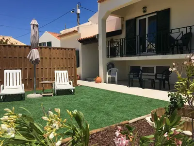 a backyard with green grass and two lawn chairs at Casa Maré in Sagres