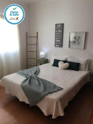 a bedroom with a bed with a blanket and pillows at Casa Maré in Sagres