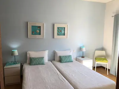 a bedroom with a bed and two tables and a chair at Casa Maré in Sagres