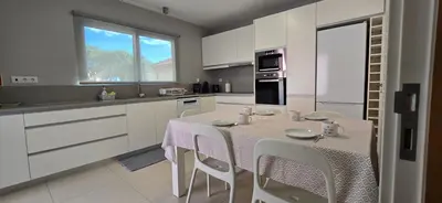 a white kitchen with a table and chairs in it at Casa da Praia in Calheta