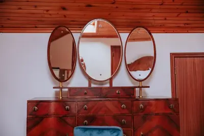 three mirrors on top of a dresser with a blue chair at Vila Mar Apartment in Ponta do Sol