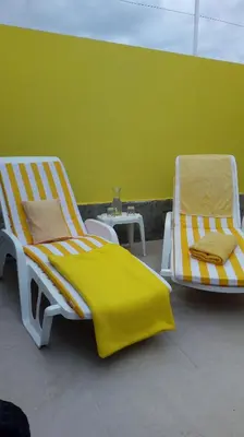 two yellow and white chairs sitting next to a green wall at Casinha Vista Mar in Porto Santo