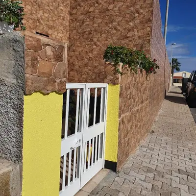 a building with a white gate and a brick wall at Casinha Vista Mar in Porto Santo