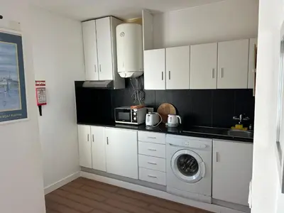 a kitchen with white cabinets and a washing machine at Magnolia Mar Apartamentos in Lagos