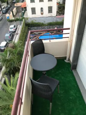 a table and chairs on a balcony with green grass at Funchal Apartment, with pool in Funchal