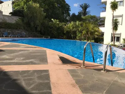a swimming pool with two metal rails next to a building at Funchal Apartment, with pool in Funchal