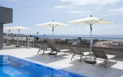 a patio with chairs and umbrellas and a swimming pool at TURIM Santa Maria Hotel in Funchal