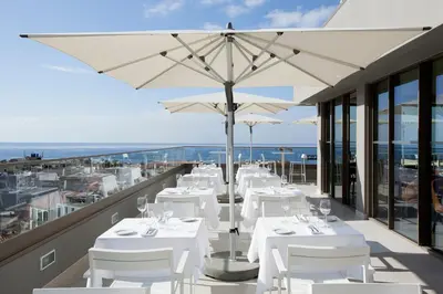 a restaurant with white tables and umbrellas on a balcony at TURIM Santa Maria Hotel in Funchal