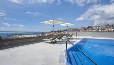 a swimming pool with chairs and umbrellas on a roof at TURIM Santa Maria Hotel in Funchal