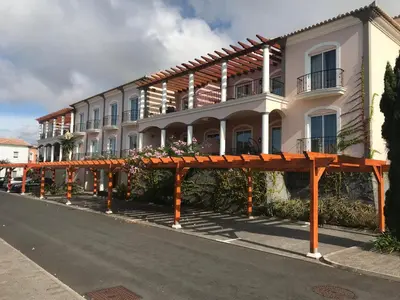 a large white building with orange posts in the street at Sea and Sun 4 You - Palheiro Village in Funchal