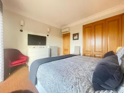 a bedroom with a bed and a tv and a chair at Sea and Sun 4 You - Palheiro Village in Funchal