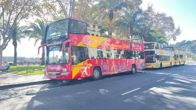a red double decker bus driving down a street at Sea and Sun 4 You - Palheiro Village in Funchal