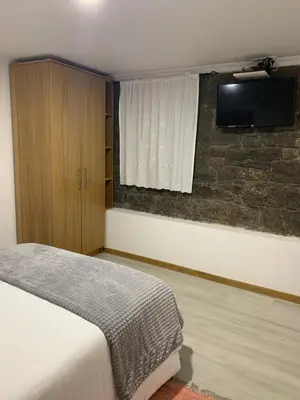 a bedroom with a bed and a television on a wall at Casa do Ribeiro Frio in Santana