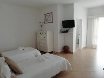 a white bedroom with two beds and a tv at Alfazema in Lagos