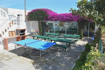 a picnic table and benches in front of a building with purple flowers at Sagres Natura in Sagres
