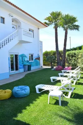 a lawn with white chairs and palm trees in front of a house at Sagres Natura in Sagres