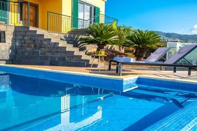 a swimming pool with chairs and stairs next to a house at Villa Sunrise View by Homie in Santa Cruz