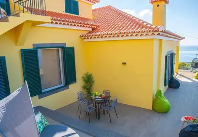 a yellow house with a table and chairs on a patio at Villa Sunrise View by Homie in Santa Cruz