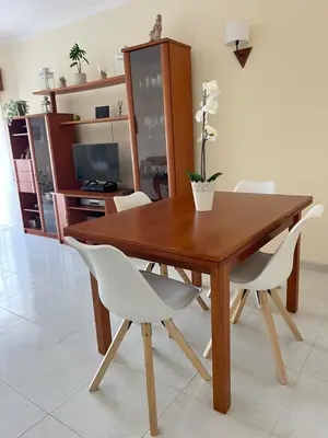 a wooden dining room table with white chairs and a television at Charming Salema in Salema