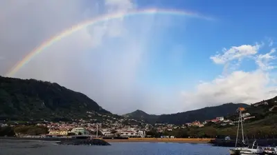 a rainbow over a body of water with a city at VIP Paradise Apartment in Machico