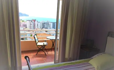 a bedroom with a view of a balcony with a table and chair at Lido Belissimo in Funchal