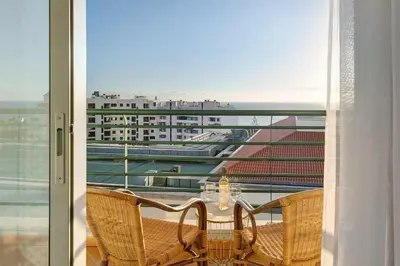 a table and chairs on a balcony with a view of a building at Oliveira Atlantic View in Funchal
