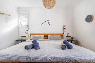 a bedroom with a large bed with blue pillows on it at Sweet Home Arrifana - Beachhouse by Lisbeyond in Praia da Arrifana