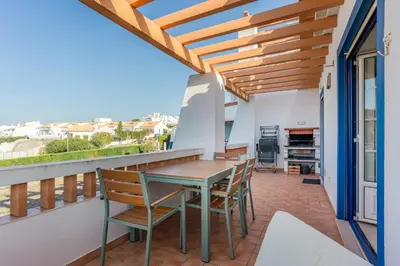 a patio with a table and chairs on a balcony at Sweet Home Arrifana - Beachhouse by Lisbeyond in Praia da Arrifana