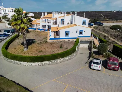 a large white house with a palm tree in a parking lot at Sweet Home Arrifana - Beachhouse by Lisbeyond in Praia da Arrifana