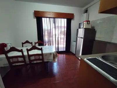 a kitchen with a table and chairs and a refrigerator at Apartamentos Lisboa in Vila do Porto