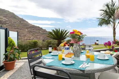 a table with fruit and juice on a patio at Zeza´s Garden in Calheta