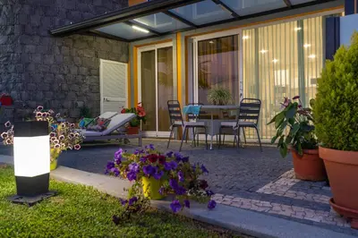 a patio with a table and chairs and flowers at Zeza´s Garden in Calheta