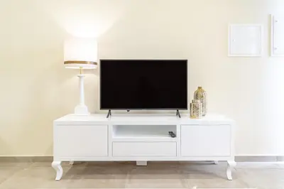 a white entertainment center with a flat screen tv on it at Zeza´s Garden in Calheta