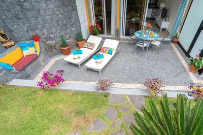 a patio with a table and chairs and flowers at Zeza´s Garden in Calheta