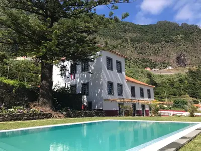 a house with a swimming pool in front of a building at Casa Oliveira Esmeraldo - Guest Houses in São Vicente