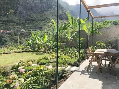 a patio with a table and a view of a garden at Casa Oliveira Esmeraldo - Guest Houses in São Vicente