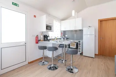 a kitchen with white cabinets and a kitchen island with bar stools at Casa Guadalupana in Arco da Calheta