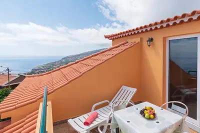 a table and chairs on a balcony with a view of the ocean at Casa Guadalupana in Arco da Calheta