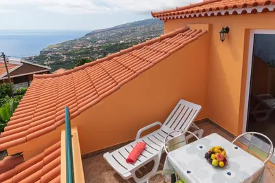 a balcony with two chairs and a table with fruit on it at Casa Guadalupana in Arco da Calheta