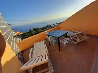 a balcony with a table and chairs and the ocean at Casa Guadalupana in Arco da Calheta