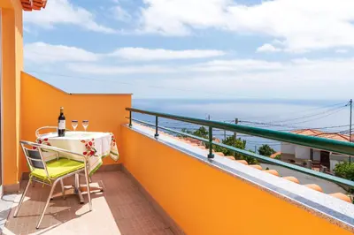 a balcony with a table and a bottle of wine at Casa Guadalupana in Arco da Calheta