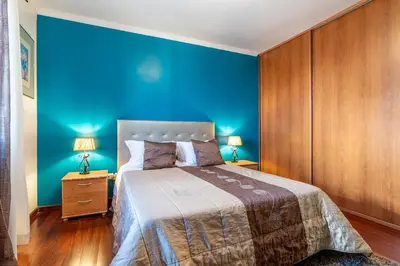 a bedroom with blue walls and a bed with two lamps at Barcelos Apartment by Holiday Rental Madeira in Funchal