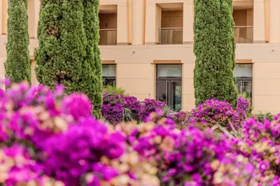 a row of trees with purple flowers in front of a building at The Navigator - Colombus Apartments & Villas in Porto Santo