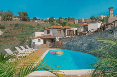 a swimming pool with chairs and a house at Vila Maria Quinta 5 