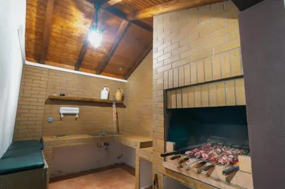 a kitchen with a brick oven with meat cooking at Vila Maria Quinta 5 