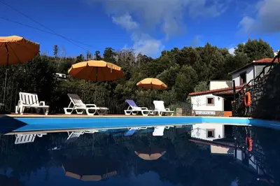 a swimming pool with chairs and umbrellas next to a house at Vila Maria Quinta 6 